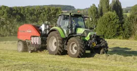 IBIO+ making bales in Austria landscape with trees on the background.
