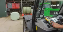 Activate a RW 1110 wrapper with a remote control in front of a barn with a Feed robot at the background.