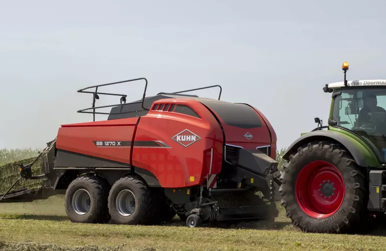 Large square baler baling in a straw field