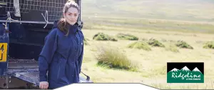 Lady in a Ridgeline Monsoon jacket in a field by a landrover