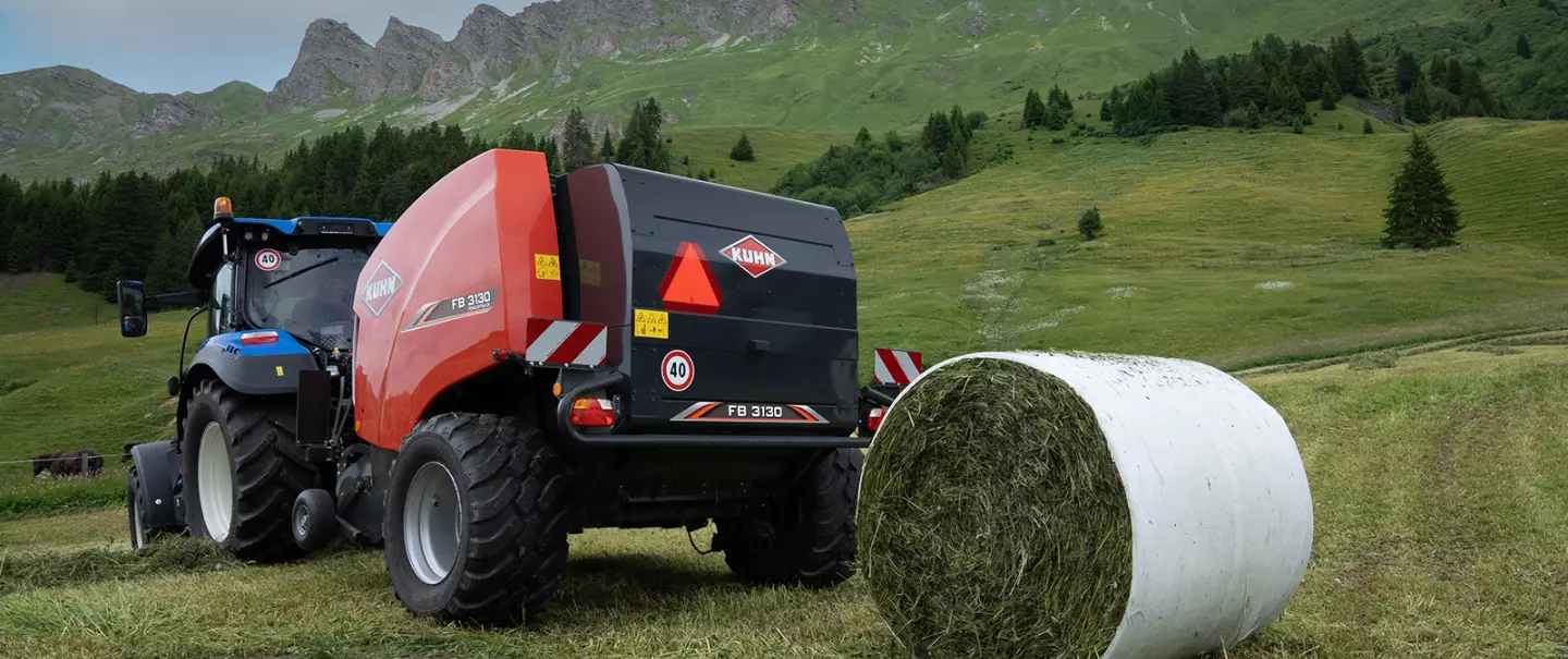 KUHN FB 3130 fixed round baler with film binding producing round bales in the mountains