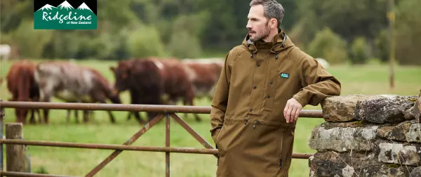 Man in field against a gate with cows in distance in Ridgeline coat