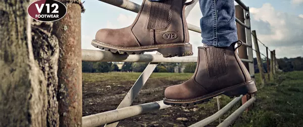 A farmer wearing dealer boots climbing a gate into field